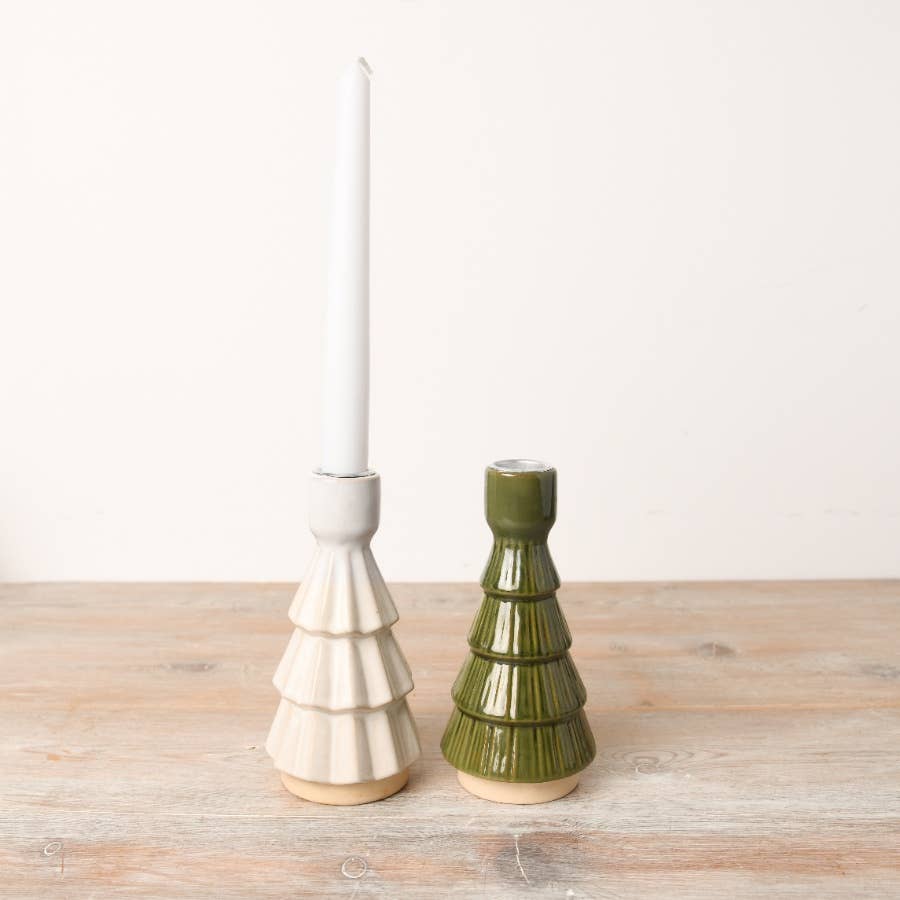 Two ceramic candle holders, one white and one green, on a wooden surface with a white background.