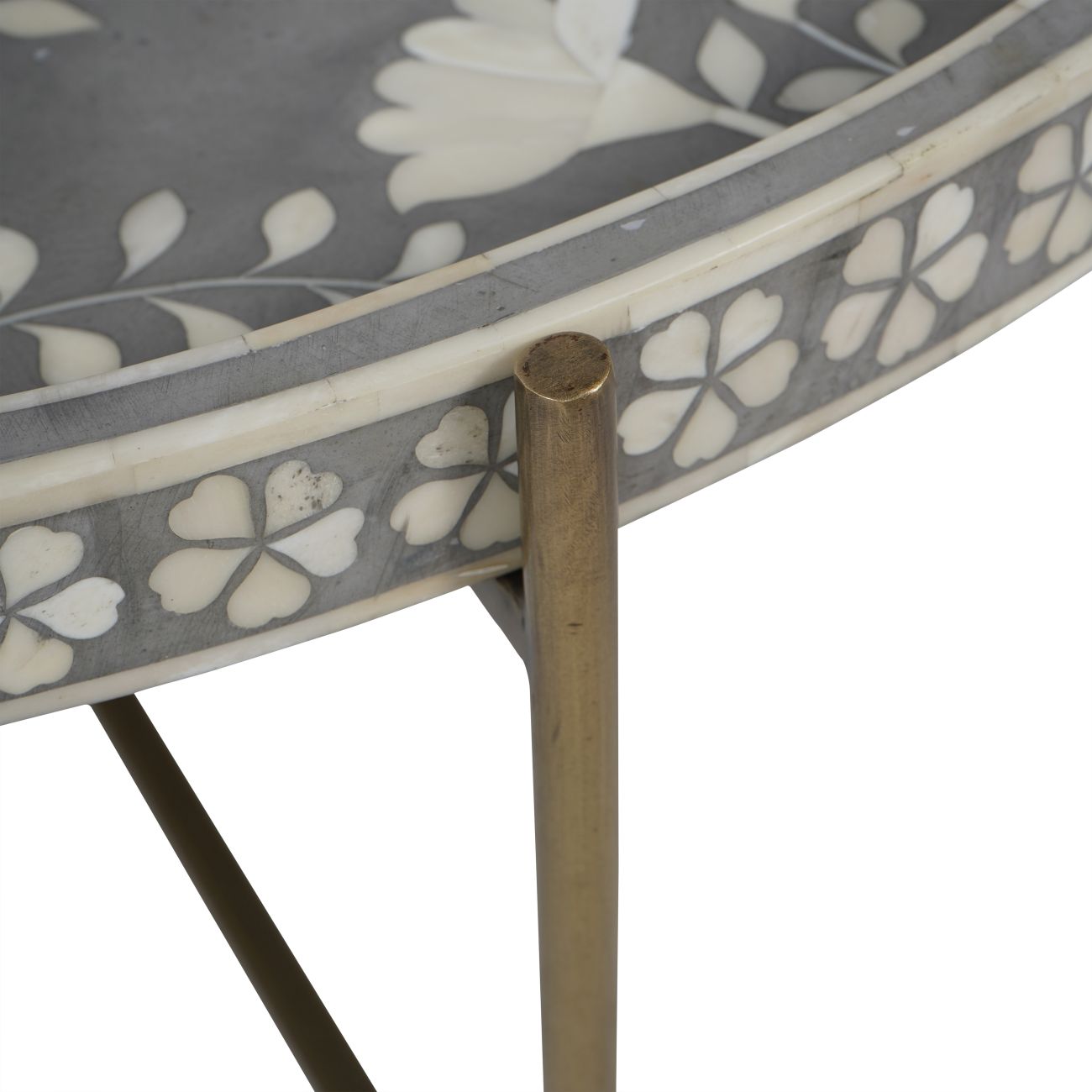 Decorative table with floral pattern and brass leg on a white background