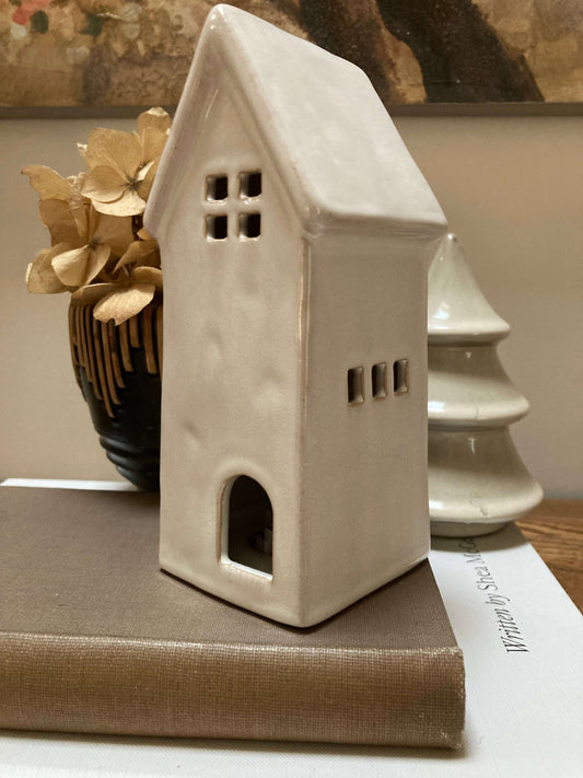 White ceramic house-shaped lantern on a surface with a blurred background