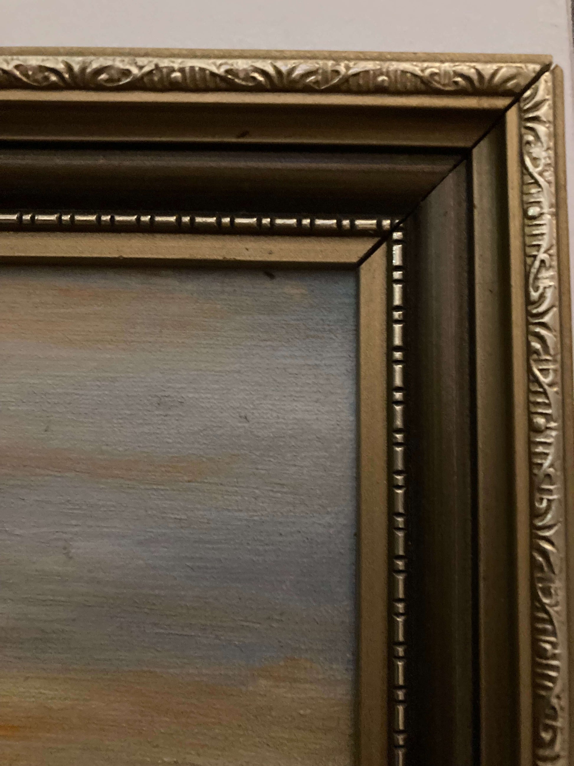 Close-up of an ornate gold picture frame with a textured surface.