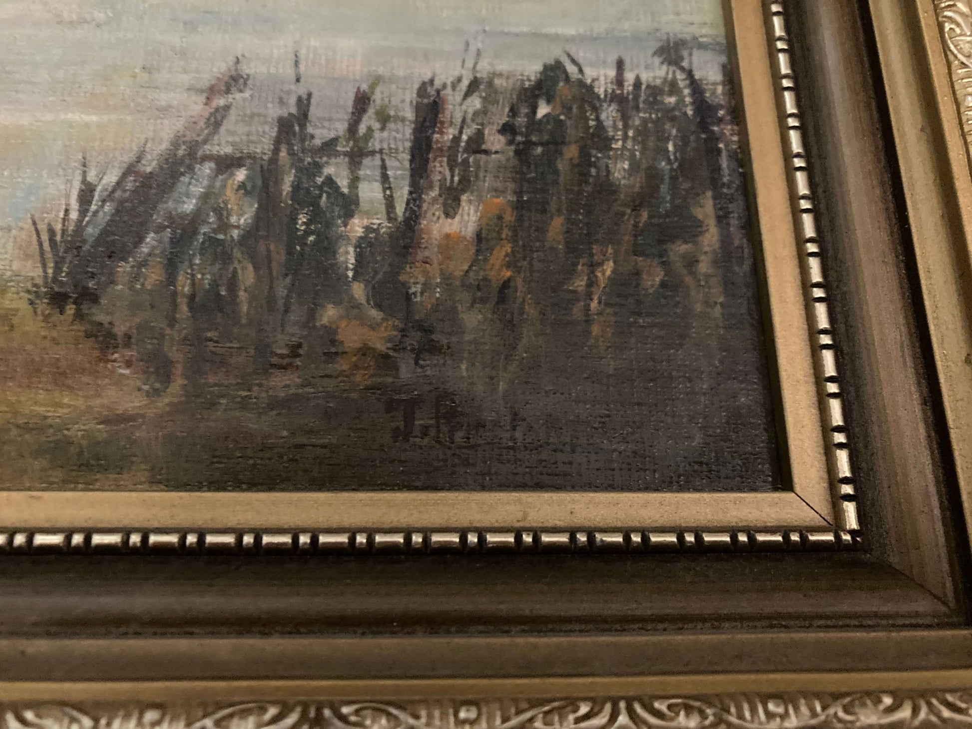 Framed painting of a landscape with trees and a signature at the bottom right corner.