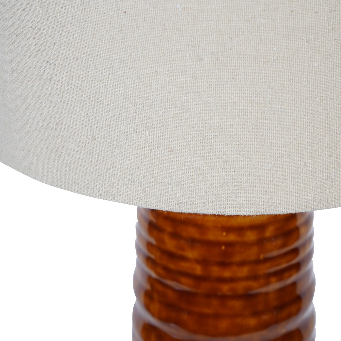 Close-up of a lamp with a textured brown base and a light neutral shade.